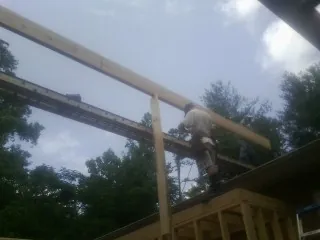 Carpenter setting a ridge beam over a new addition frame — Ice Dam Removal by Roofing Brothers in Honey Grove