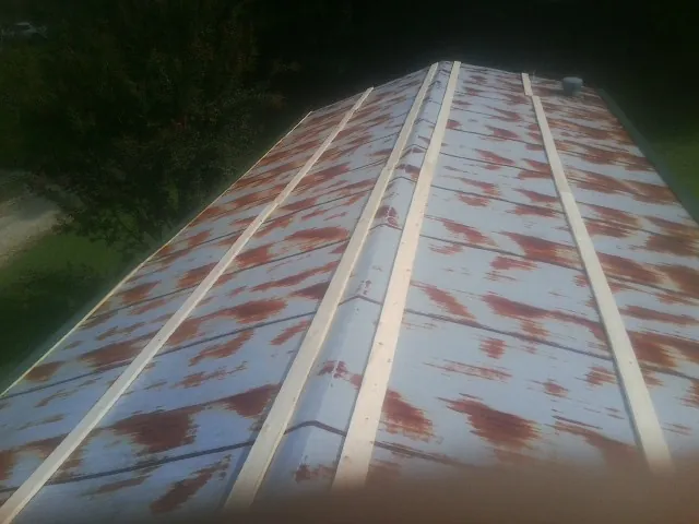 Rusted metal roof panels with new wood purlins before replacement — Storm Damage Roof Repair in Honey Grove by Roofing Brothers
