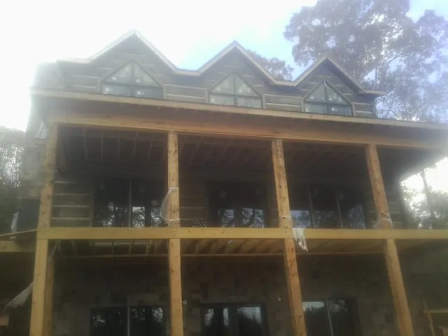 Dormers and porch framing on a large log home under construction — Roof Coating work by our crew in Honey Grove