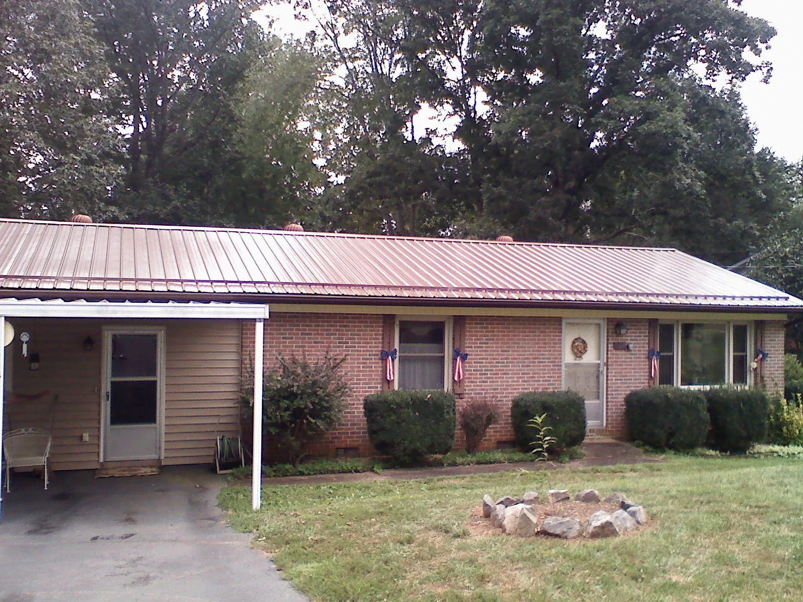 Bronze metal roof and carport on a brick ranch home — Roof Repair work by our crew in Honey Grove