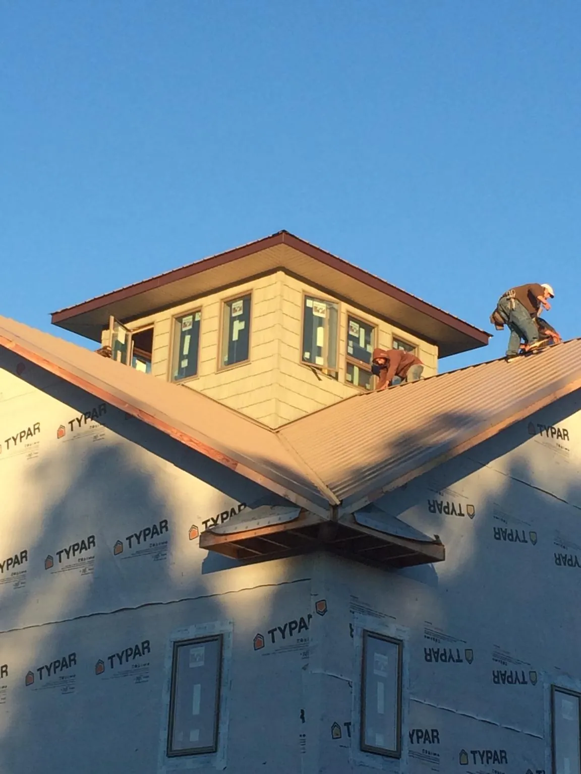 Roofers working around a rooftop cupola on a new metal roof at sunset — Roof Waterproofing in Honey Grove by Roofing Brothers